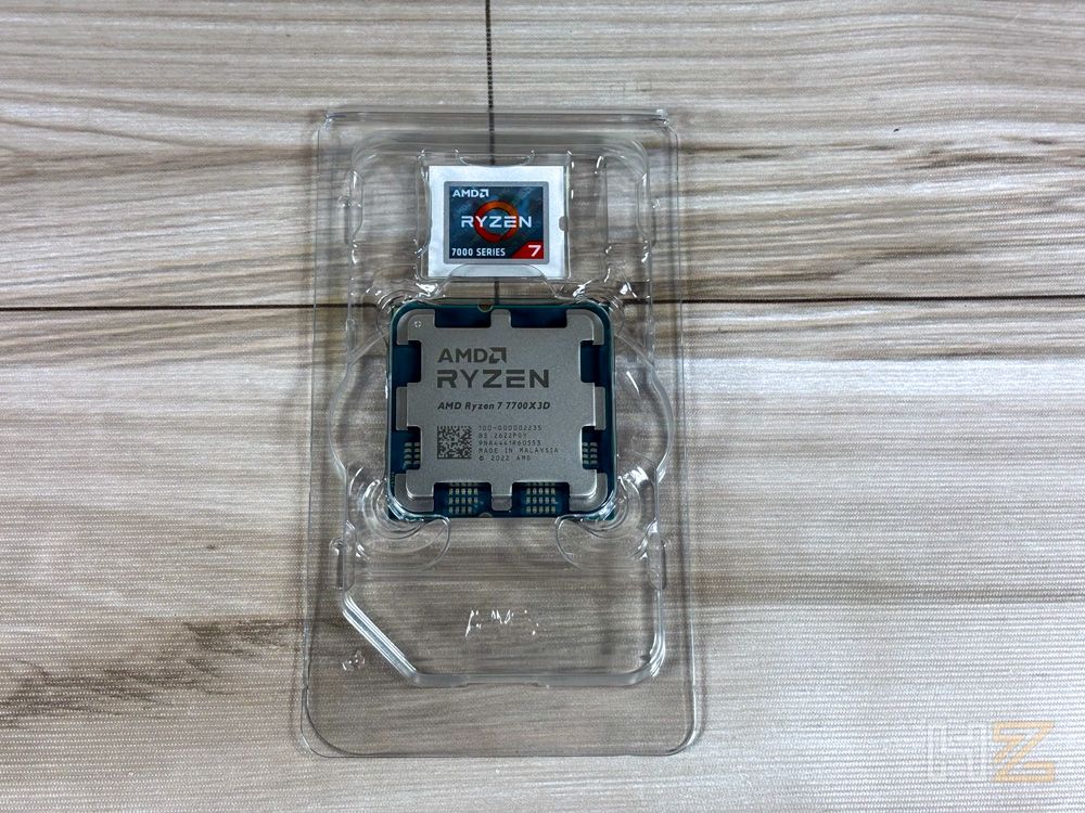 Procesador AMD Ryzen 7 7700X3D en su blíster de plástico de protección sobre una superficie de madera clara.