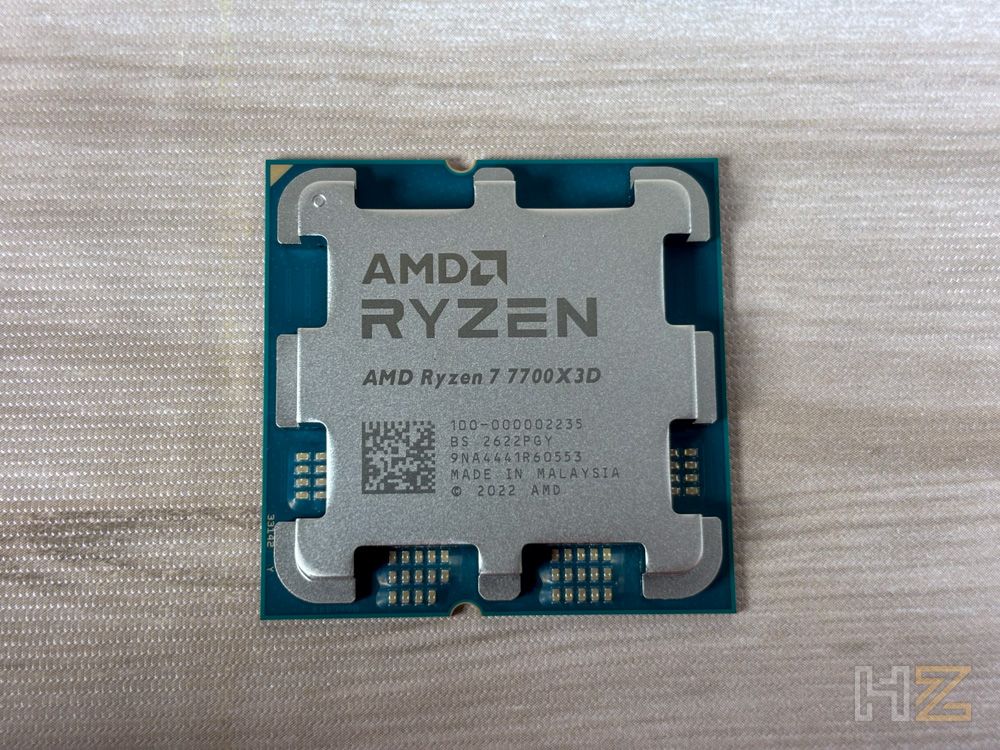 Procesador AMD Ryzen 7 7700X3D con su IHS de diseño característico sobre una superficie de madera clara.