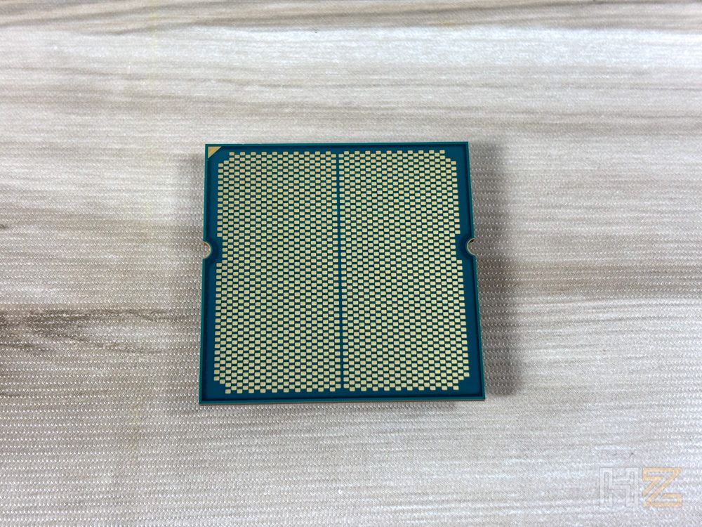 Vista inferior de un procesador AMD Ryzen donde se aprecian los puntos de contacto dorados del socket AM5 sobre un fondo de madera clara.