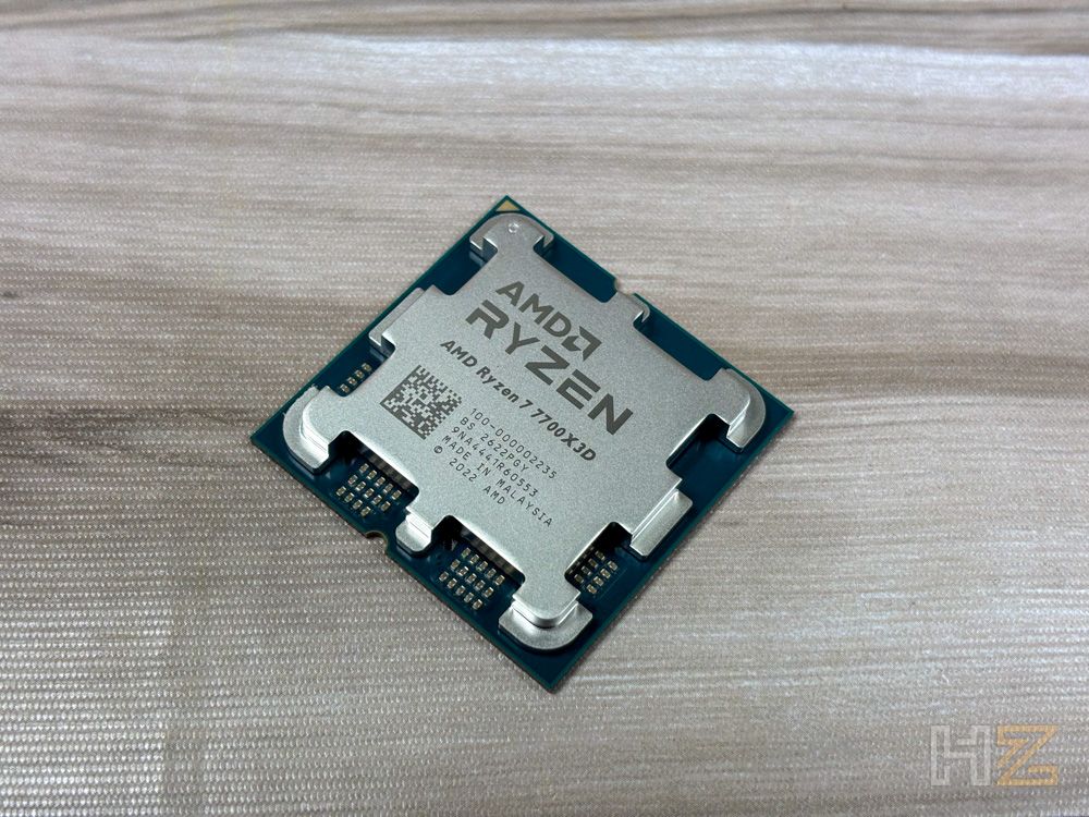 Procesador AMD Ryzen 7 7700X3D con su difusor de calor metálico sobre una superficie de madera clara.