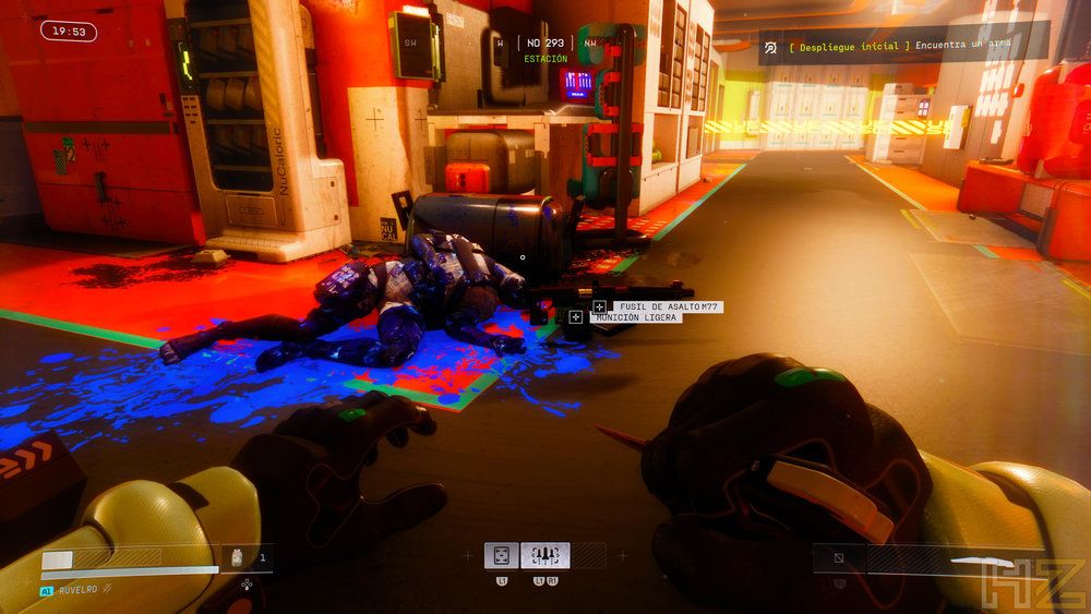 Vista en primera persona de un videojuego de disparos con un enemigo abatido sobre un charco de sangre azul en un entorno futurista industrial.