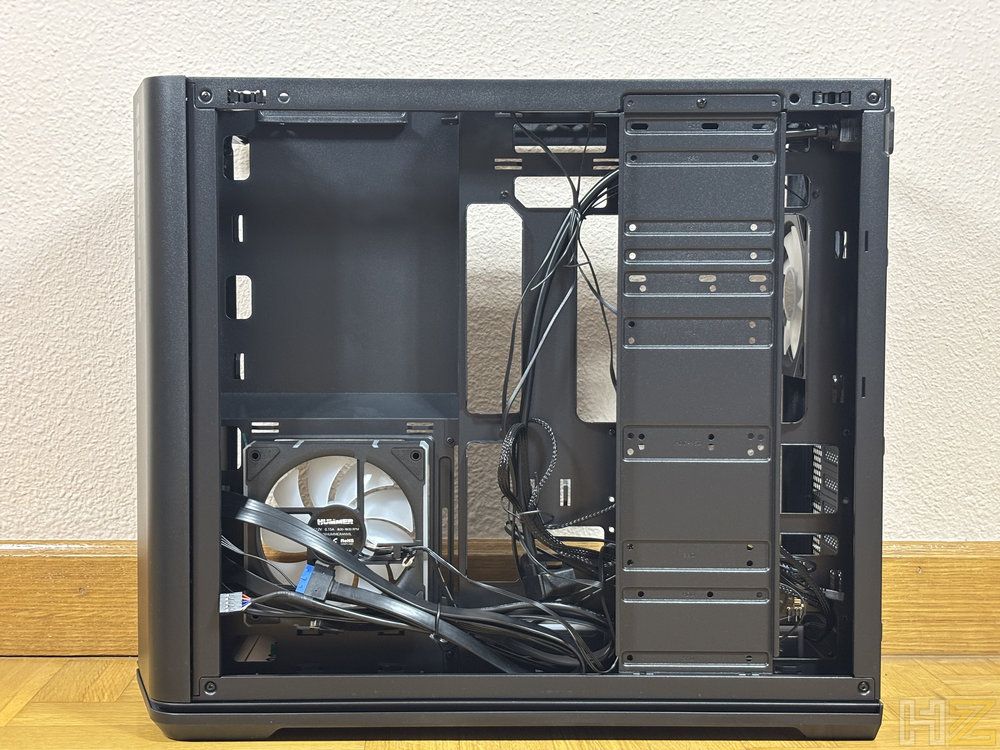 Interior lateral de una torre de ordenador Nox Hummer Anvil con gestión de cables y compartimentos para unidades de almacenamiento.