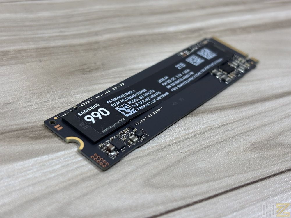Unidad de almacenamiento SSD Samsung 990 Pro de 2 TB con formato M.2 dispuesta sobre una superficie de madera clara.