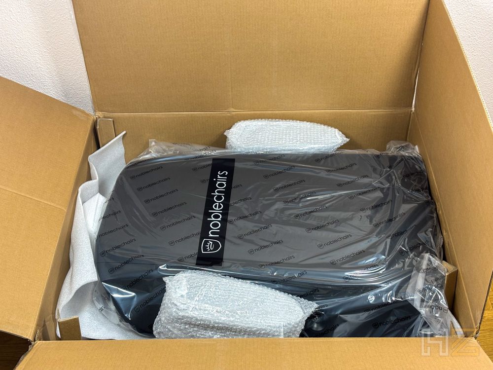 Respaldo de una silla noblechairs dentro de su caja de embalaje con protecciones de plástico y espuma.